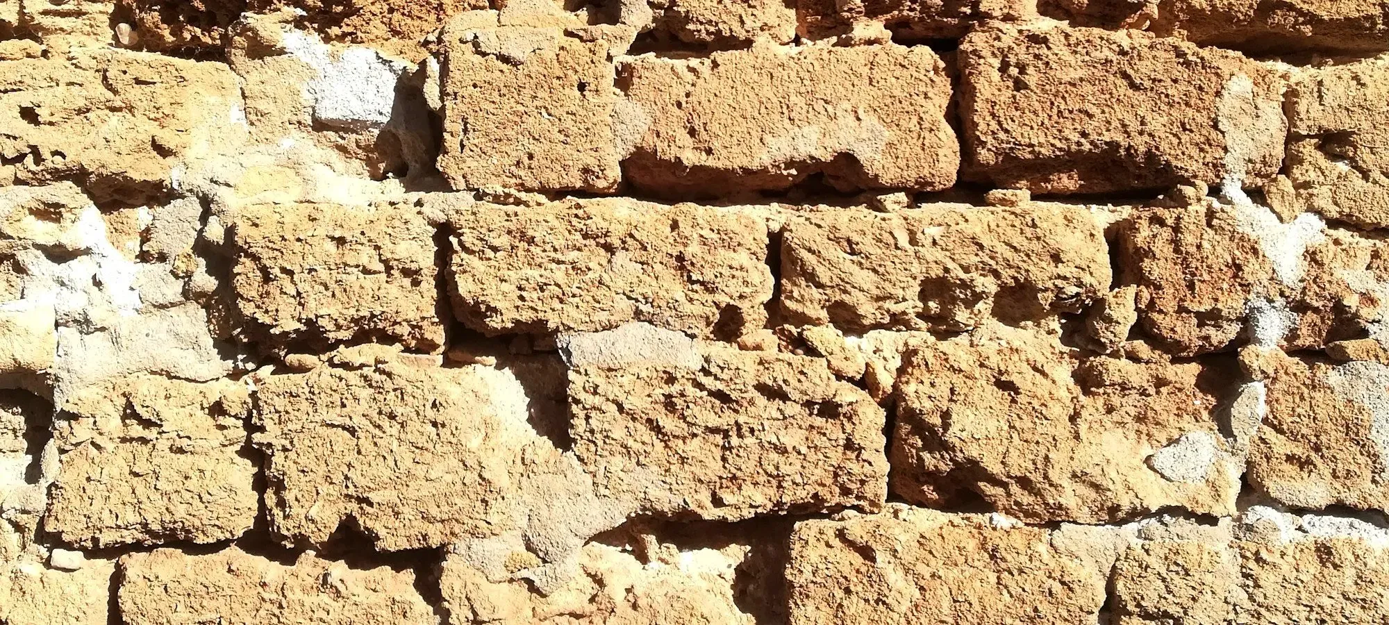 Eine Mauer aus grob behauenem Kalkstein in der Mittagssonne.